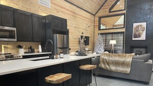 Una cocina moderna con una isla central, armarios negros y electrodomésticos de acero inoxidable.