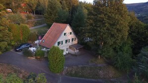 A house with a sloped roof, a fenced yard, and a car parked outside. - Beautiful gîte in Alsace (Natzwiller)
