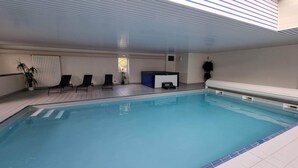 An indoor swimming pool with a tiled floor, a bench, and a few lounge chairs. - Beautiful gîte in Alsace (Natzwiller)