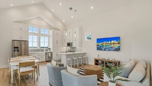 Een ruime keuken met witte kasten, een centraal eiland en een eetgedeelte met een ronde tafel en stoelen.
