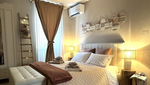 A neatly arranged bedroom with a bed, bedside tables, a bench, and a decorative wall piece.