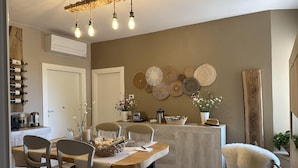 A dining area with a wooden table, chairs, and a kitchen counter with various items.