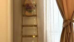 A wooden ladder with lights and a basket with flowers against a wall.