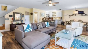 A living room with a sofa, a coffee table, and a dining area with chairs and a table.
