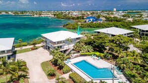 A coastal resort with a swimming pool, beachfront villas, and clear turquoise waters.