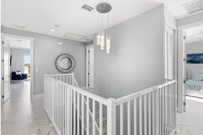 A modern interior with a white railing, a circular wall decoration, and a hanging light fixture.