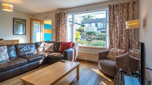 A living room with a sofa, armchair, coffee table, and a TV. - Skylark Cottage -  a single-level, two-bedroom property on the gentle slopes of Wansfell Pike, yet o (Ambleside)