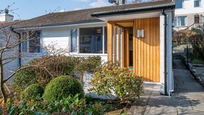 A residential house with a wooden front door, a satellite dish, and a garden with various plants. - Skylark Cottage -  a single-level, two-bedroom property on the gentle slopes of Wansfell Pike, yet o (Ambleside)
