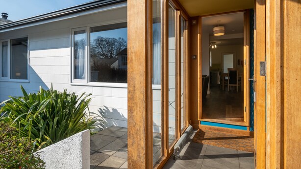 A modern house with a large sliding glass door leading to a well-lit interior. - Skylark Cottage -  a single-level, two-bedroom property on the gentle slopes of Wansfell Pike, yet o (Ambleside)