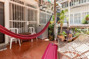 A covered patio with a hammock, chairs, and potted plants. - Vp101a Zona1 in Rio de Janeiro (Rio de Janeiro)