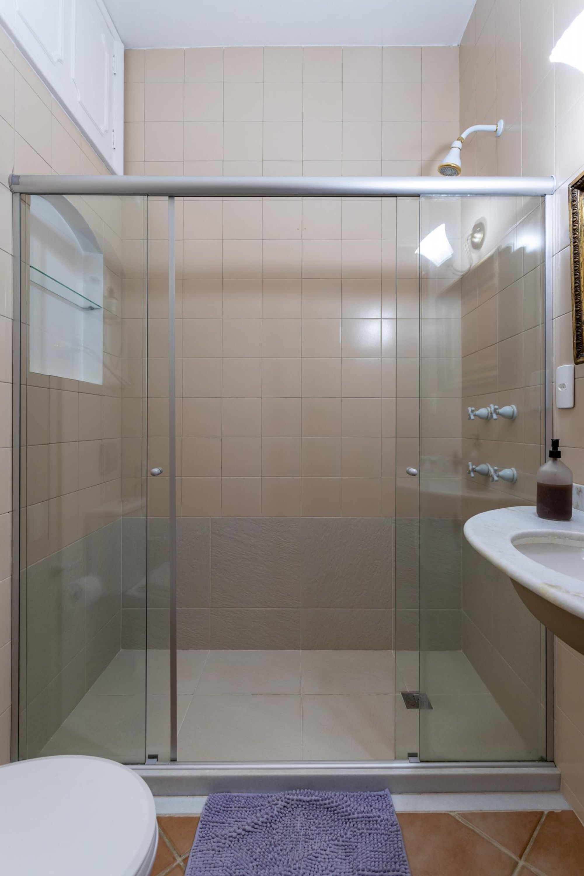 Een moderne badkamer met een douchecabine van glas, een wit wastafelmeubel en een toilet.