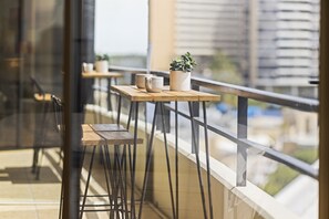 A balcony with wooden tables and chairs, a potted plant, and two white cups. - Beautiful Waterfront Retreat with Marina Views, Pool/hot tub/gym (Marina Del Rey)
