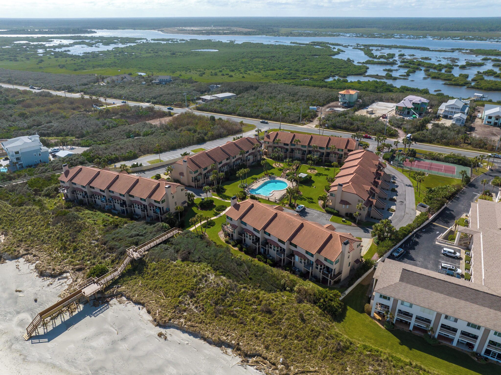 A resort with multiple buildings, a swimming pool, and a beach area.