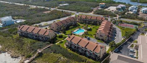 A resort with multiple buildings, a swimming pool, and a beach area.