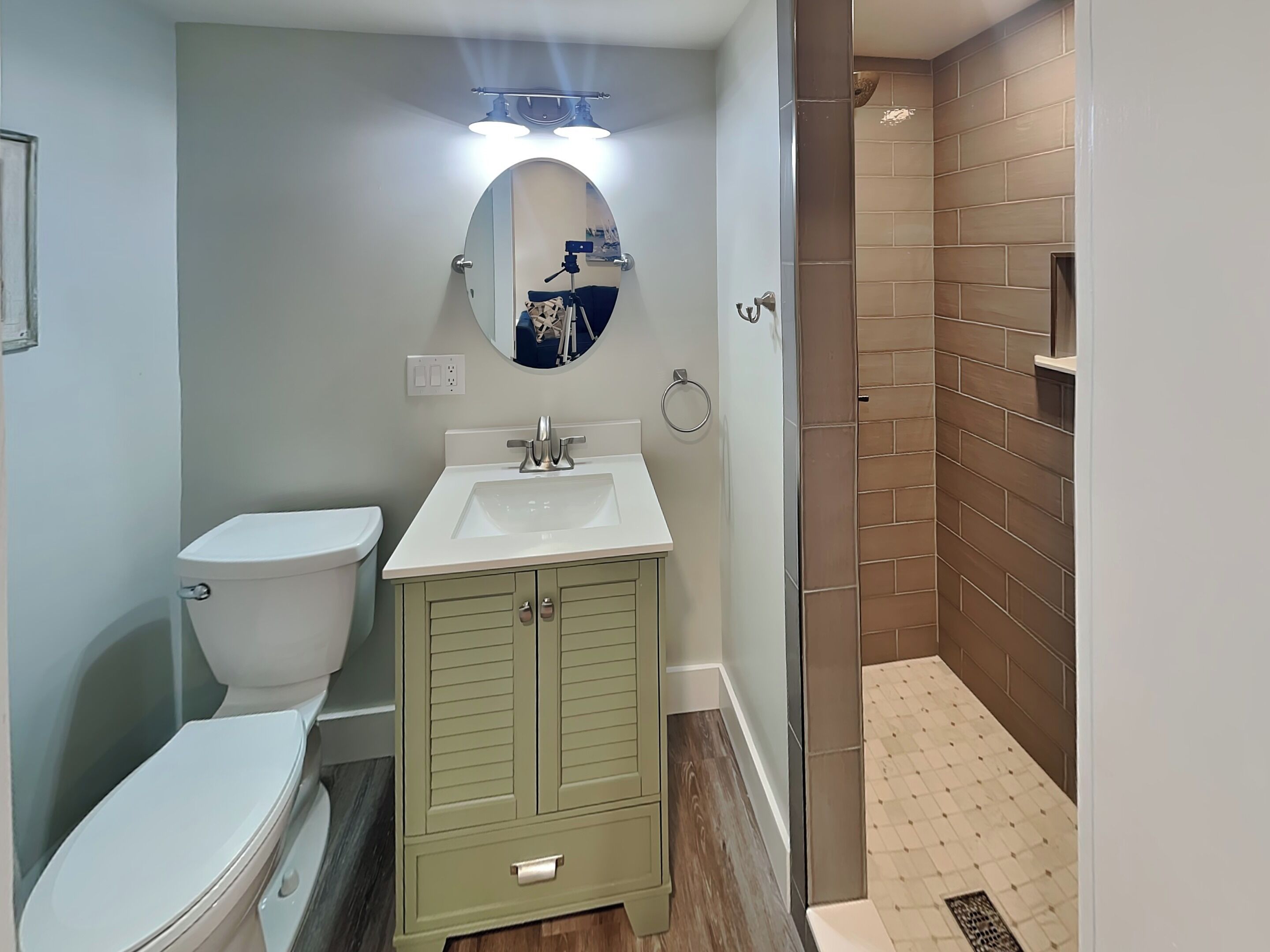 A bathroom with a toilet, sink, and mirror.
