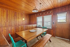 A wooden dining area with a table and benches, a ceiling fan, and a door with a window.