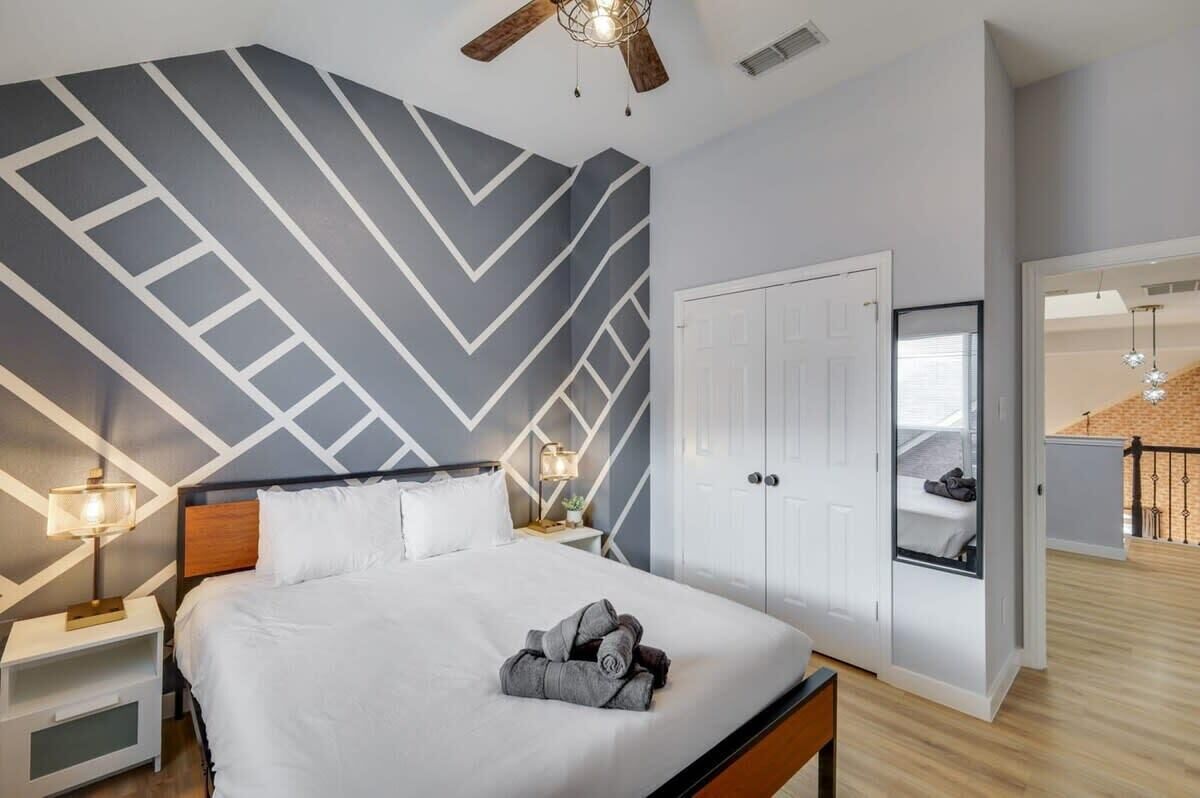 A modern hotel room with a bed, a nightstand, a lamp, a wardrobe, and a view of the balcony.