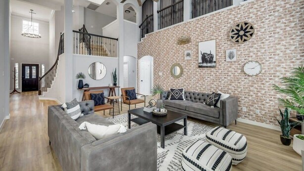 Un salon spacieux avec un mur en briques, un escalier et un ventilateur de plafond.