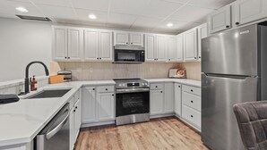 Une cuisine moderne avec des armoires blanches, des appareils en acier inoxydable et un plancher en bois.