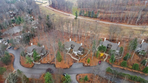 Vue aérienne d’un quartier résidentiel avec de nombreuses maisons, des rues et une zone boisée.