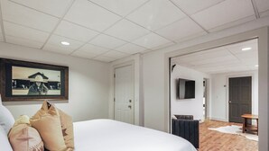 Une chambre d’hôtel avec un grand lit, un tableau encadré au mur, une télévision et un plancher en bois.