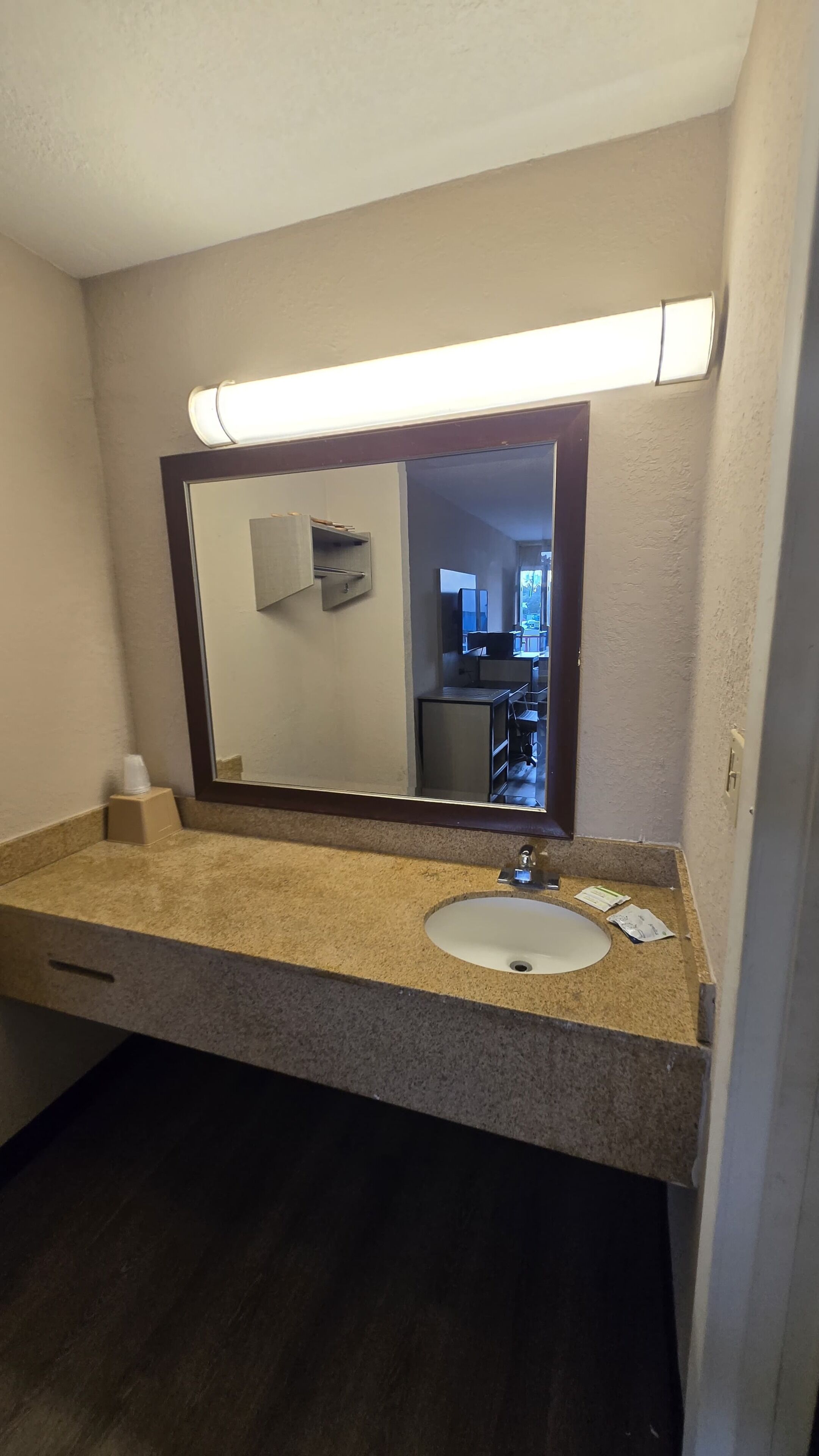 A bathroom with a sink, mirror, and a light above the mirror.