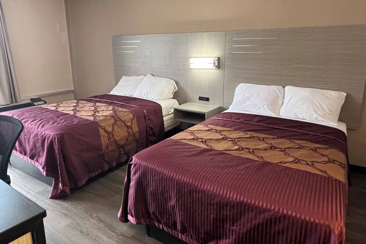 Habitació d'hotel amb dos llits, cada un amb capçalera, taulella i làmpada.