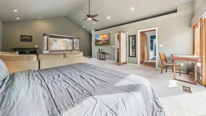Un dormitorio amplio con una cama grande, ventilador de techo y vistas al exterior.