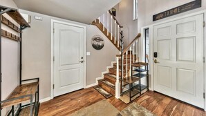 Una escalera con escalones de madera y barandillas blancas, que conduce a una plataforma con una puerta blanca y un letrero en la pared.