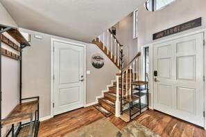 A staircase with wooden steps and white railings, leading to a landing with a white door and a wall-mounted sign.