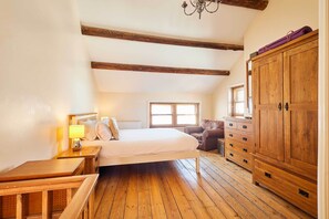 A bedroom with a wooden floor, a bed, a nightstand, a dresser, and a window. - Host & Stay | Sea Haven (Staithes)