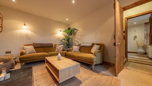 A cozy living room with a wooden coffee table, two sofas, and a large plant. - Maurice Cottage, Docking, Norfolk (Docking)