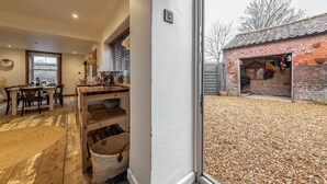 A spacious kitchen with a large window, wooden flooring, and a dining area with a table and chairs. - Maurice Cottage, Docking, Norfolk (Docking)