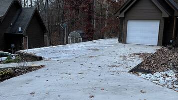 A residential driveway with a garage, a basketball hoop, and a small shed.