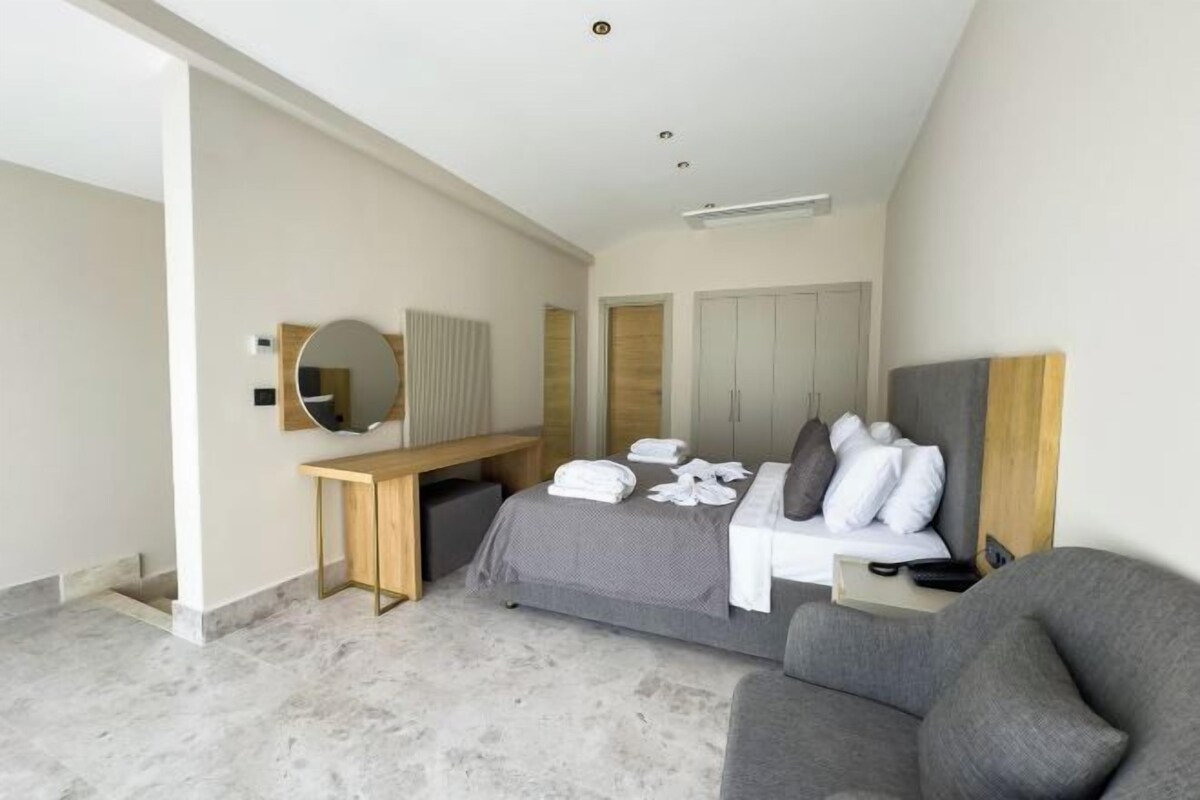 A modern hotel room with a bed, a desk, a chair, and a large mirror.
