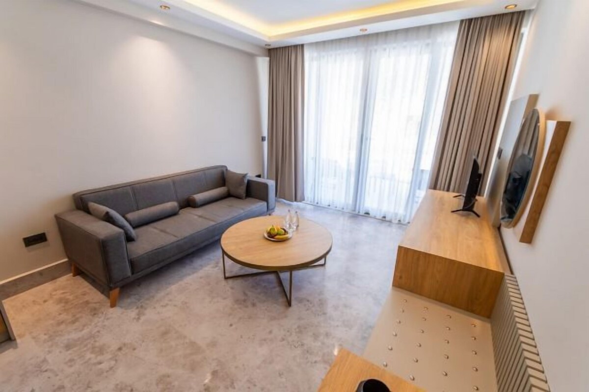 A modern living room with a grey sofa, a round coffee table, and a wooden side table.