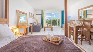 Een hotelkamer met een bed, een eettafel, een bank en een balkon met uitzicht.