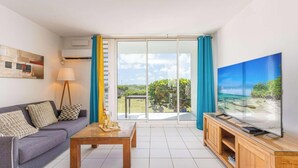 Een moderne woonkamer met een bank, salontafel, televisie en een balkon met uitzicht.