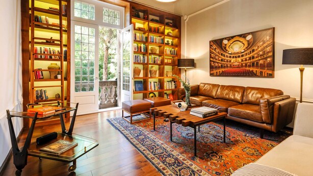 A cozy living room with a leather sofa, a coffee table, and a bookshelf filled with books. - Casa Wynwood in Roma Norte (Ciudad de México)
