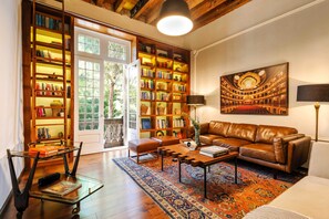 A cozy living room with a leather sofa, a coffee table, and a bookshelf filled with books.