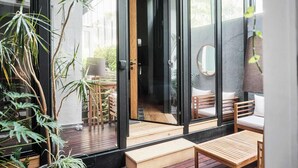 A modern outdoor seating area with wooden furniture, a glass door entrance, and potted plants. - Casa Wynwood in Roma Norte (Ciudad de México)