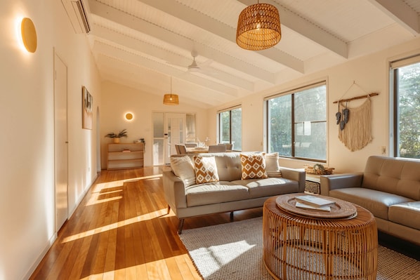 A spacious living room with a sofa, a round coffee table, and a large window providing natural light.