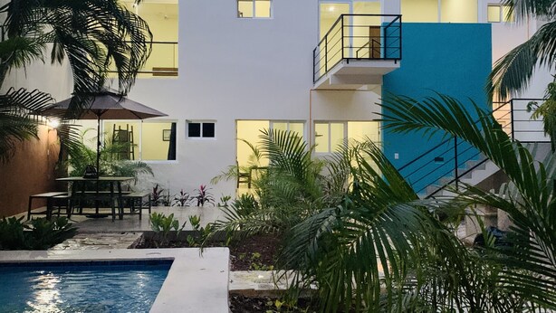 A modern multi-story building with a pool, outdoor seating, and palm trees. - Charming studio with a nice pool (Playa del Carmen)