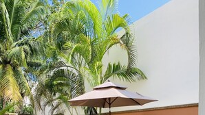 A patio area with a pool, a table and benches, and various plants. - Charming studio with a nice pool (Playa del Carmen)