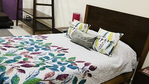 A bed with a floral quilt, a wooden headboard, and two pillows with a leaf pattern. - Charming studio with a nice pool (Playa del Carmen)