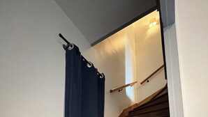 Una escalera de madera con barandilla y una cortina azul.