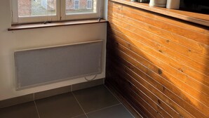 Una cocina con ventana, pared de madera y radiador.