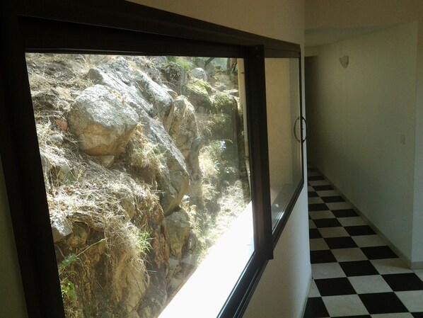 A corridor with a checkered floor and a large window overlooking a rocky outdoor area. - Close to the beaches, spacious, air conditioning, panoramic view of the gulf! (OLMETO)