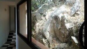 A hallway with a black and white checkered floor leading to a window with a view of rocky terrain and trees. - Close to the beaches, spacious, air conditioning, panoramic view of the gulf!  (OLMETO)