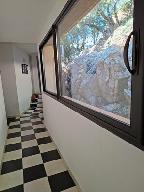A hallway with a checkered floor and large windows offering a view of rocky terrain.